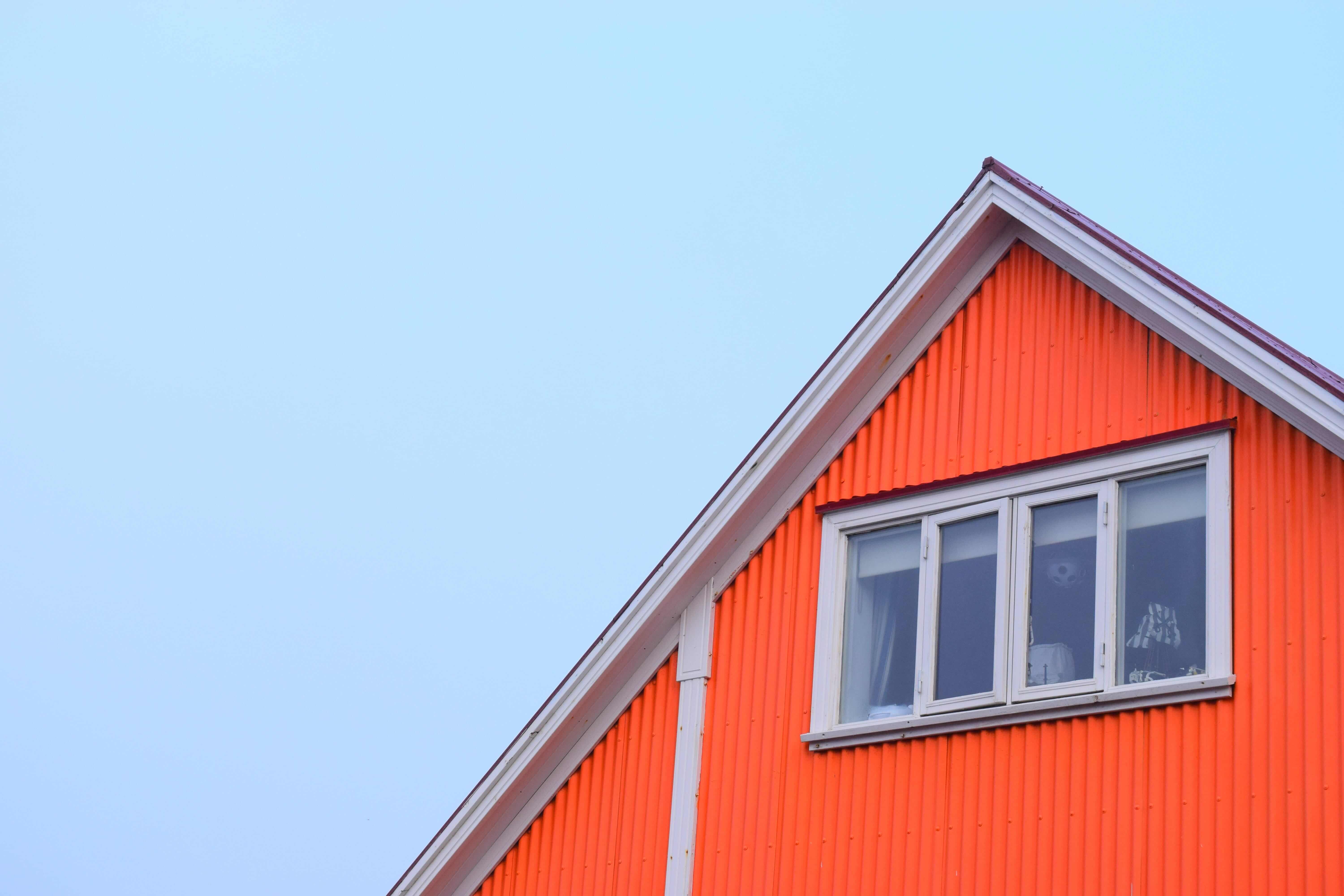 The top portion of an A-frame house painted bright orange.  