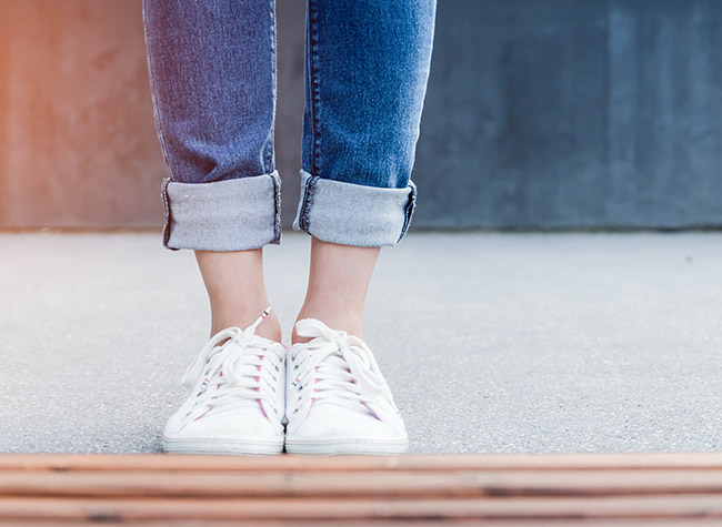 image of someone's feet with sneakers and jeans