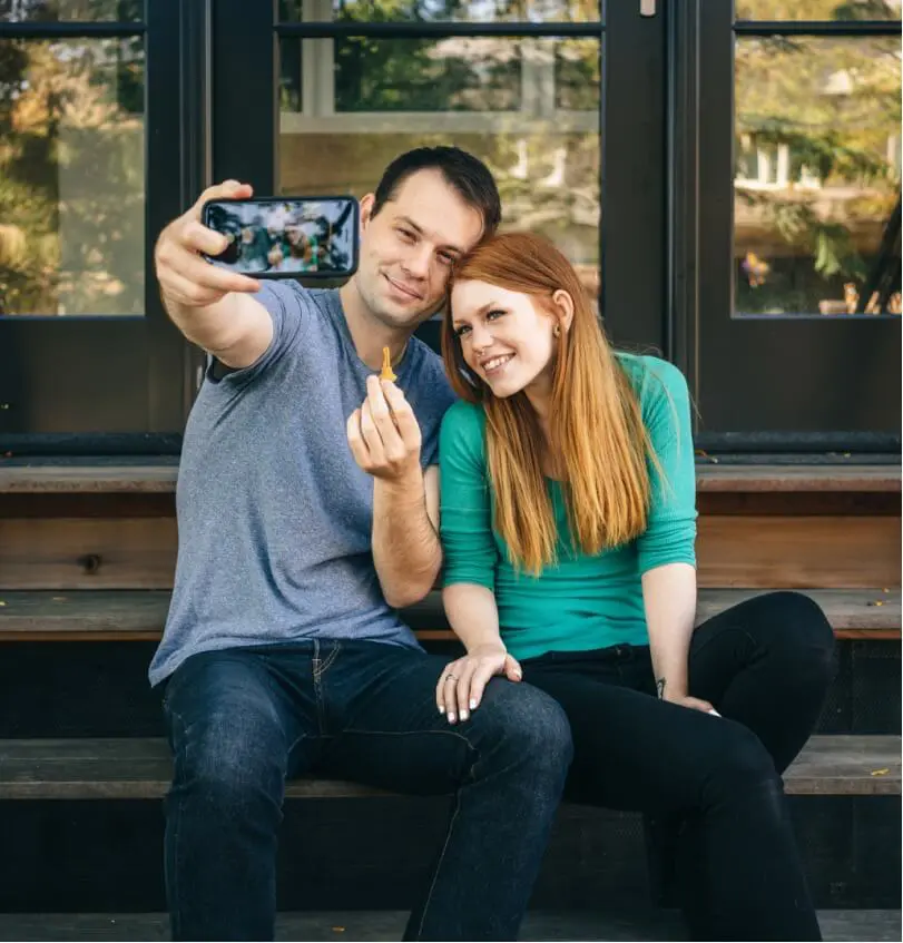 Two people smiling and taking a self photo while holding a key.