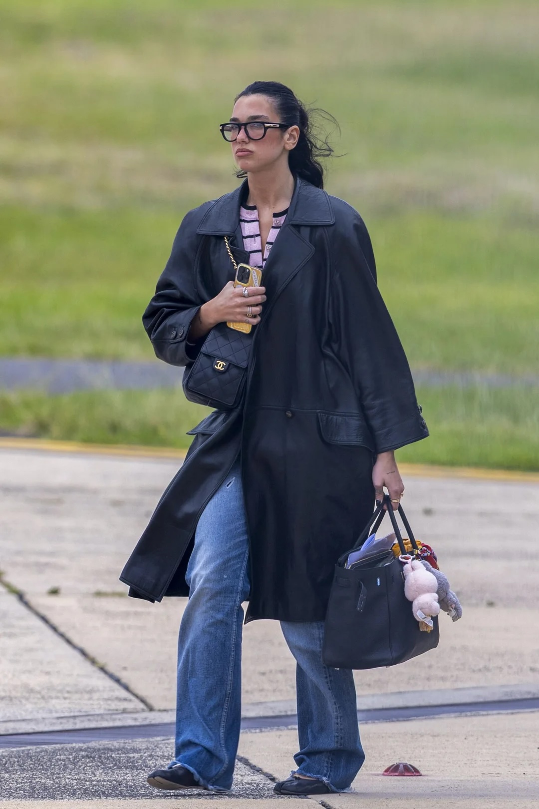 Woman in black coat carrying tote bag with plush keychains