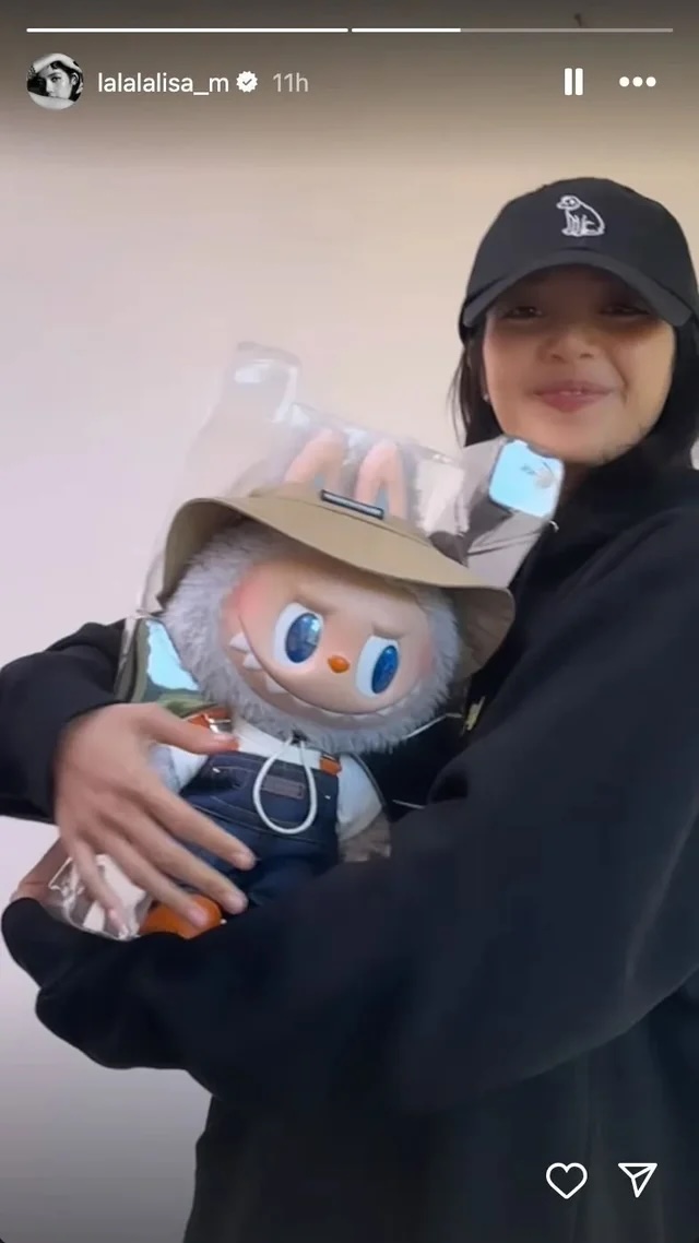 Woman in black cap smiling while holding boxed Labubu figure