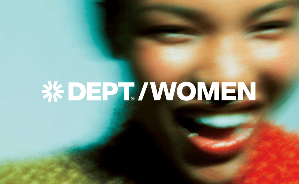 Logo for "DEPT/WOMEN" in white against a motion-blurred close-up of a smiling woman's face with bright red lipstick and a colorful, textured sweater.