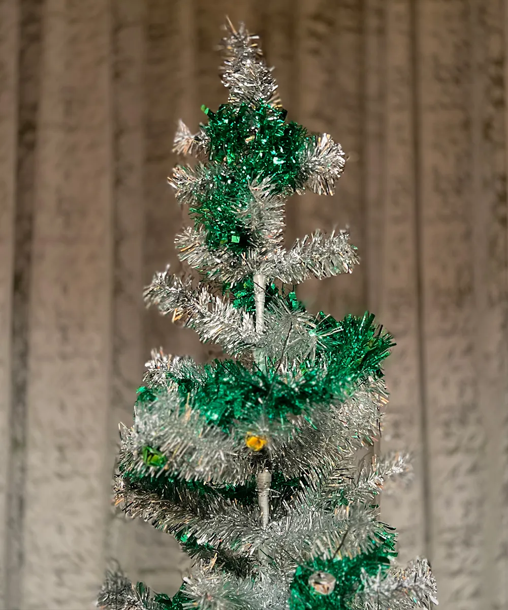 Close-up of a vintage Christmas tree decorated with silver and green tinsel.