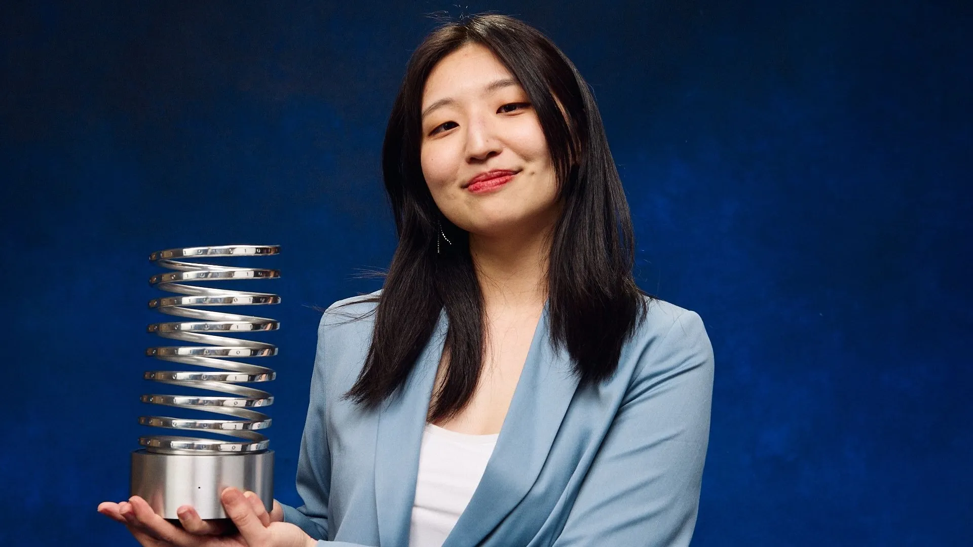 Woman holding an award in front of a blue background